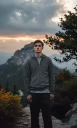 a young man is standing on top of a mountain