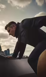 a man in black jacket climbing up the roof of a vehicle
