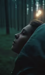 a girl looking out the window in a forest with a street lamp in the background