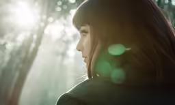 the woman in the forest is looking at the trees