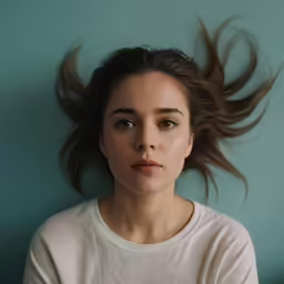 a woman in a white shirt looks ahead with long hair blowing behind her