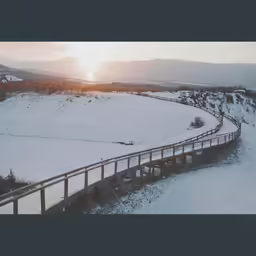 an aerial shot of a snow covered landscape and road