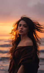 a woman in a brown dress near the ocean