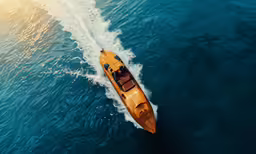 a yellow boat floating in blue water with a red seat