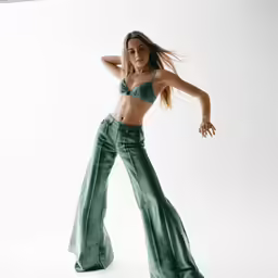 a beautiful young woman standing on one leg wearing a green outfit