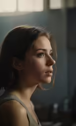 a woman looks off into the distance while she stands in front of a window