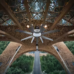 ceiling fan with light bulbs shining on it, at top of a bridge