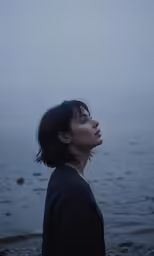 woman staring up at water on foggy day