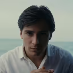 a man wearing a white shirt near the ocean