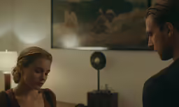 a woman and man standing next to each other looking at something on the counter
