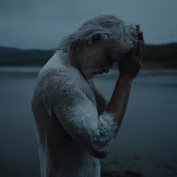 the man has white hair and beard in snow by the water