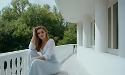 a woman sits on a white porch