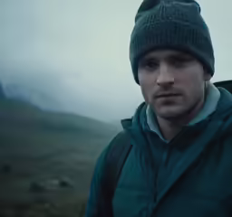 a man wearing a beanie standing on a mountain