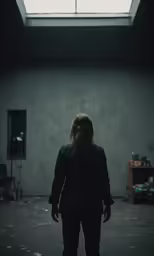 a woman standing in an empty room with the skylight above