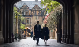 two people walking under an archway that connects to buildings