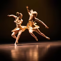 two people dressed in gold ballet clothes are on the stage
