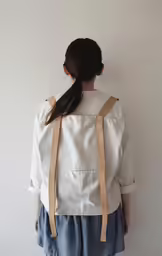 a woman wearing a white top and a pair of brown suspenders