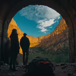 people in the sun, looking at some mountains, through an archway