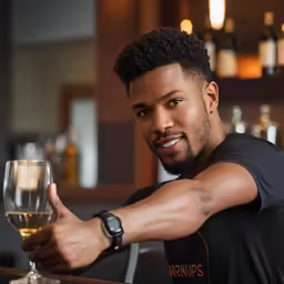a young man is sitting at a bar with a glass of wine
