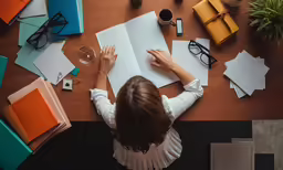 woman writing in a book on a table