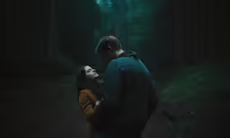 a man and woman standing in the middle of a forest looking at each other