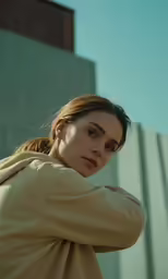 woman in jacket looking away outdoors near building