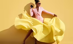 a woman in a pink dress holding a black purse