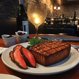 a plate of meat and slices of strawberries on a table