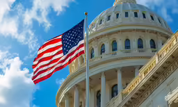 the united states flag waving in front of a domed building