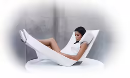 a woman wearing short shorts sits in a white reclining chair