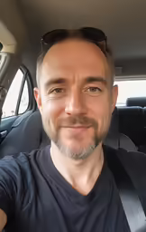 a man with glasses sitting in the passenger seat