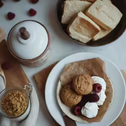 small bowls of cookies and strawberries next to a cup of coffee and jar of jam