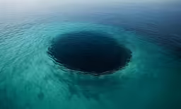 blue ocean water is near a large hole