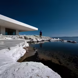 a man standing on top of a beach next to a building