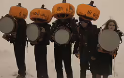 four people wearing orange hats holding drums and drumsticks