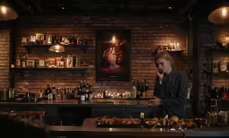 a man sitting at a bar surrounded by bottles