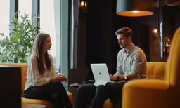 two people at desk with laptops on their lap
