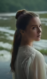 a girl stands in the water with a hair roll in her bun