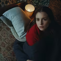 a woman laying on her side next to a candle