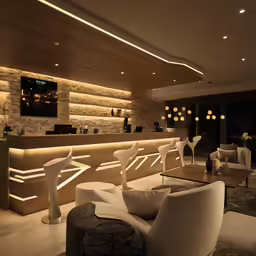 a living room with chairs and tables surrounded by wooden paneling