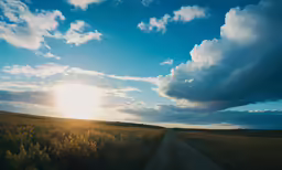 the sun setting over the countryside next to a road
