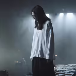 a woman stands alone on a foggy bed