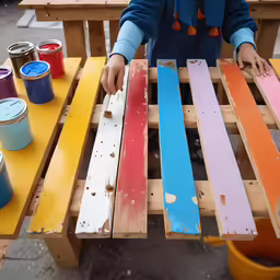 child holding and painting colorful wooden pallets