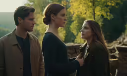 a group of people standing around each other looking at something