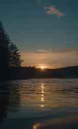 the sun is setting over the mountains in the water