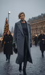 a woman in grey coat and black pants on street