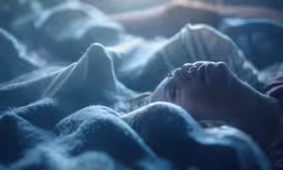 there is a woman sleeping in bed with a blanket over her