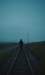 a person walks along train tracks in the dark