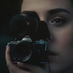 a woman holding a camera and looking at her face