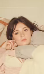 a girl laying in bed under the blanket